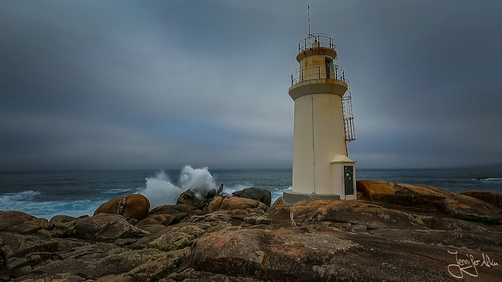 Leuchtturm Faro de Muxia mit tosenden Wellen und spritzender Gischt an der rauen Küste der Costa da Morte.