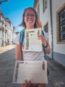 Pilgerin Jennifer Alka zeigt stolz ihre Compostela-Urkunde in Santiago de Compostela