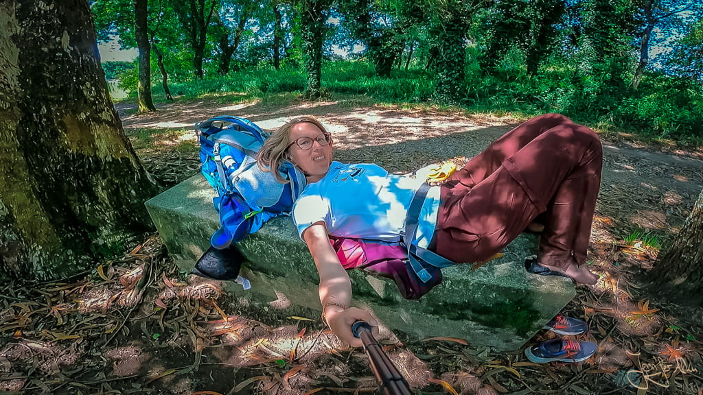 Pilgerin Jennifer Alka liegt auf Steinbank am Camino Espiritual wegen Beinkrämpfen