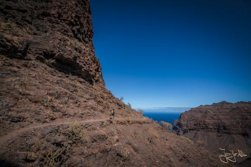 Ein schmaler Pfad führt an steilen Felswänden entlang - Die Wanderung zum Strand Güi Güi