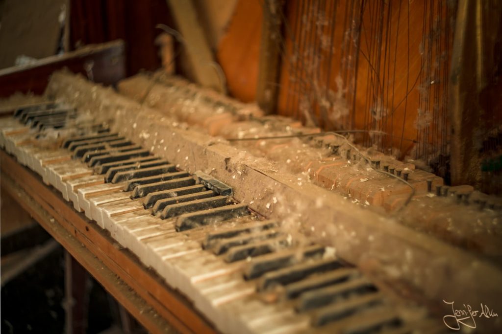 Dieses Bild zeigt ein Klavier das von einer dicken Staubschicht bedeckt ist.