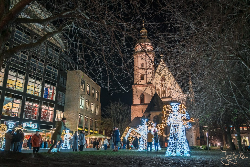 Dieses Bild zeigt den Weihnachtsmarkt Leipzig 2023. Du siehst beleuchtete Engelsfiguren vor der Thomaskirche am Markt in Leipzig